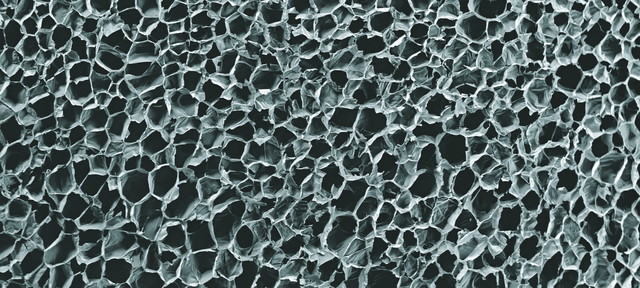 Polystyrene foam. Coloured scanning electron micrograph (SEM) of a section through a block of extruded polystyrene foam, showing the internal closed-cell air spaces.